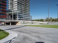 the entrance to a building in a park next to a parking area with cars, and people walking across the street