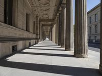 there are columns on the walkway in a building with a sky background and sunlight shining down