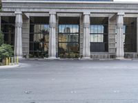 a building with pillars and columns across the road from a parking lot with chairs in front