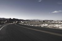 a person rides down an empty road in the mountains of the desert with mountains behind him