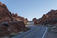 a long road lined with red rocks in the desert near a rock formation and desert area