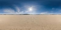 a desert area with a lone field of sparse grass and sand blowing towards the sky