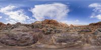 a desert scene with rocks and a hill with sparse vegetation and rocks on the ground