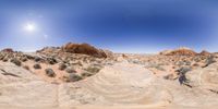 a rocky outcrop in the middle of the desert is seen through a fisheye lens