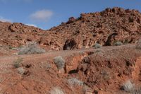 people riding on horseback through the desert on a trail in the distance are red mountains