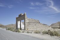 an old building stands on the side of the road in the desert near some hills