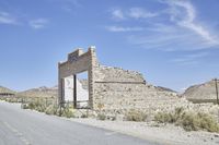 an old building stands on the side of the road in the desert near some hills
