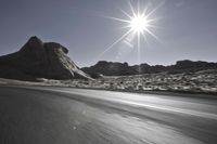 sun shining over the desert and rocky hill behind a motorcycle rider on an all road highway