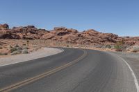 a lone motorcycle is traveling through the desert road in front of a mountain top formation