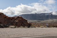 a view of some rocks mountains and a road with a traffic sign below it that reads