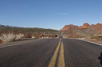 an empty highway runs through the mountainous desert landscape on a clear day in the afternoon