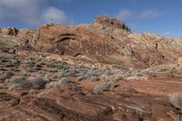 a view of a red rock and rocky landscape in the mountains near an area with bushes and sparse brush