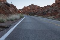 a road runs past rocks and has an orange fire hydrant on the side of the road