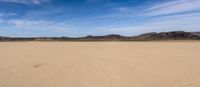 there is a very wide open field in the desert with mountains in the background and a trail leading to the horizon