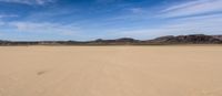 there is a very wide open field in the desert with mountains in the background and a trail leading to the horizon