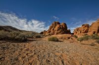 rocks and a dirt ground on a sunny day with blue sky in the background, a trail through