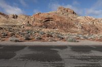 a car is parked in a parking lot beside the mountains in nevada, on an asphalt road