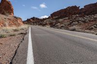 a mountain road is surrounded by rocky walls and a single road sign that points to the left