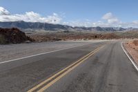 a mountain scene with one way road going through the desert to mountain peaks in the distance