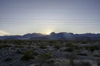 the sun sets in between mountains and power lines in the desert in nevada, nevada