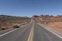 a long stretch of empty road going past some mountain ranges at a scenic location near nevada