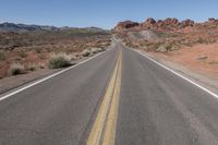 a long stretch of empty road going past some mountain ranges at a scenic location near nevada