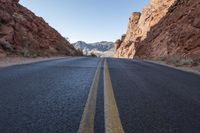 a winding road runs through rocky cliffs on both sides of it and the middle of a narrow road with a single yellow line