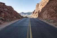 a winding road runs through rocky cliffs on both sides of it and the middle of a narrow road with a single yellow line