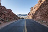 a winding road runs through rocky cliffs on both sides of it and the middle of a narrow road with a single yellow line