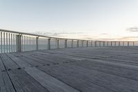 a person sits on a bench next to the ocean in the morning, and looks over the boardwalk