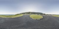 a panoramic photo shows the road and grassy land that has just gone under construction