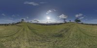 a 360 - view of green grass and clouds and hills at the top of a hill