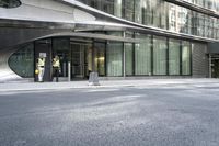 a building with a curved metal facade and windows on it's side by the street