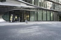 a building with a curved metal facade and windows on it's side by the street