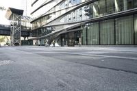 a building with a curved metal facade and windows on it's side by the street