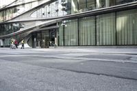 a building with a curved metal facade and windows on it's side by the street