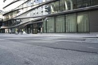 a building with a curved metal facade and windows on it's side by the street