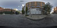 a circular photo of a building in the middle of a street with cars parked nearby