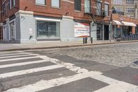 a city street with an old brick building next to a cobble stone street and sidewalk