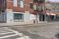 a city street with an old brick building next to a cobble stone street and sidewalk