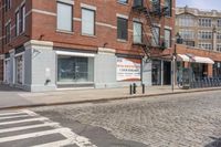 a city street with an old brick building next to a cobble stone street and sidewalk