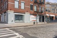 a city street with an old brick building next to a cobble stone street and sidewalk