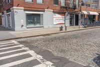 a city street with an old brick building next to a cobble stone street and sidewalk