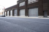 a building with a number of windows is behind an empty street lined with parked cars