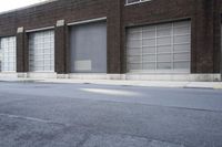 a building with a number of windows is behind an empty street lined with parked cars
