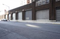 a building with a number of windows is behind an empty street lined with parked cars