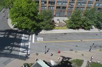 a bus stop and trees next to a sidewalk and street with several people standing on it