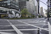 a stoplight near a large art piece on a city street corner in new york