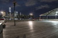 a view of new york city skyline at night from pier on the hudson river side