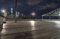 a view of new york city skyline at night from pier on the hudson river side